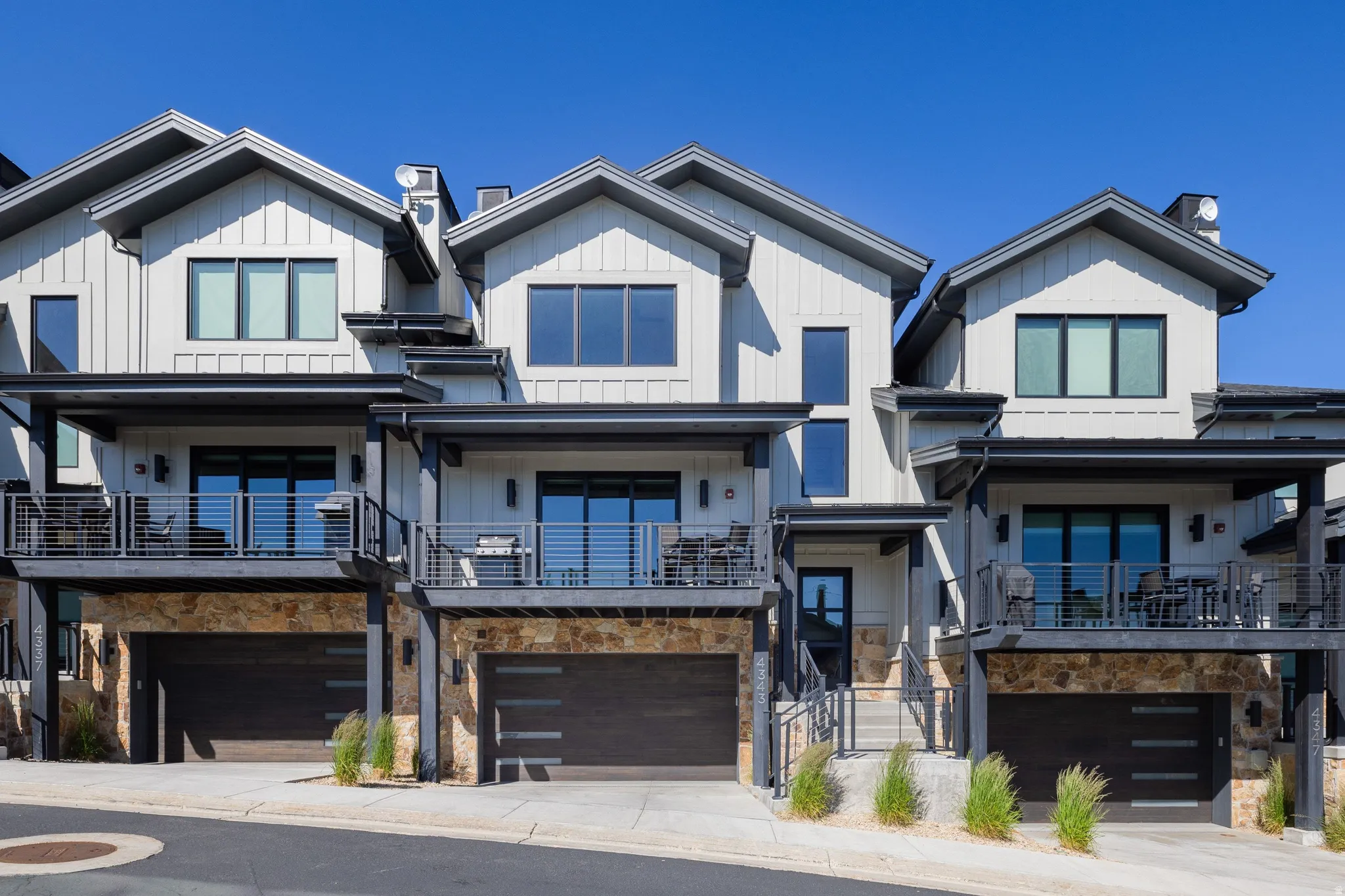 Modern townhome exterior featuring vertical white siding and dark trim
