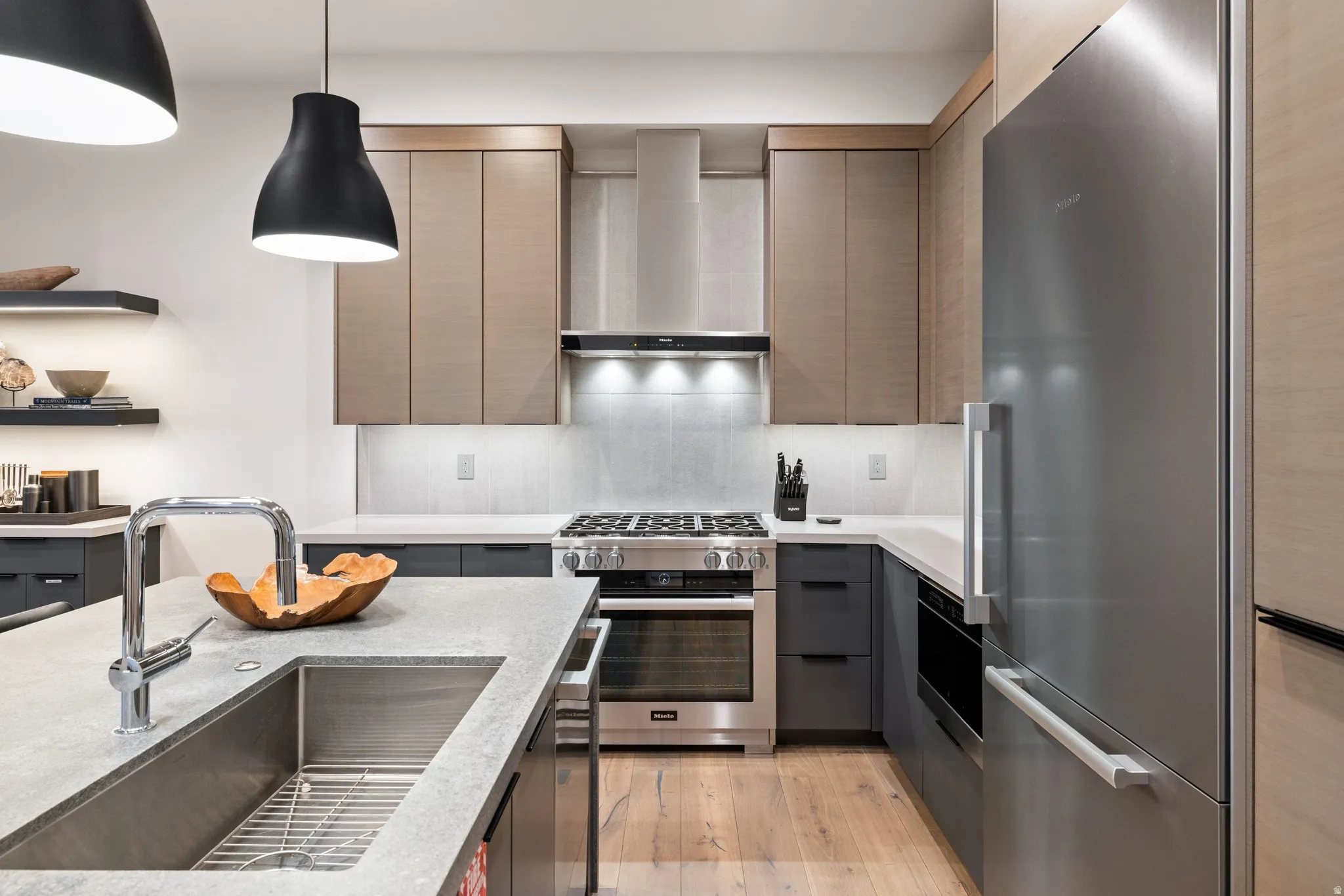 Modern kitchen featuring a stainless steel gas range, integrated refrigerator, and wood-finish flooring