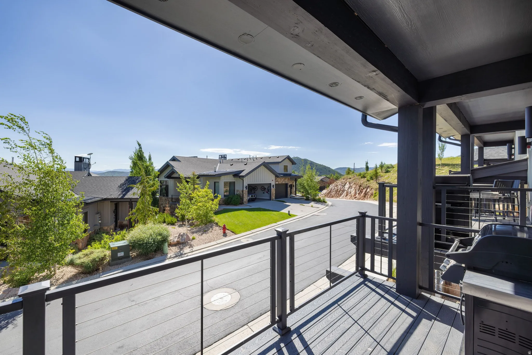 Covered outdoor deck with composite decking, black metal railing, and recessed lighting