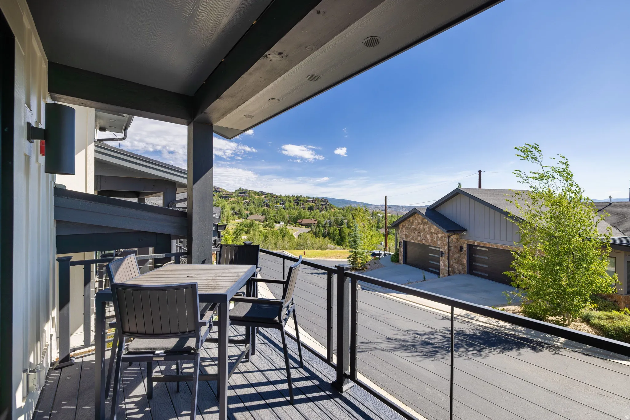 Expansive outdoor balcony featuring composite decking, a glass panel railing, and recessed lighting