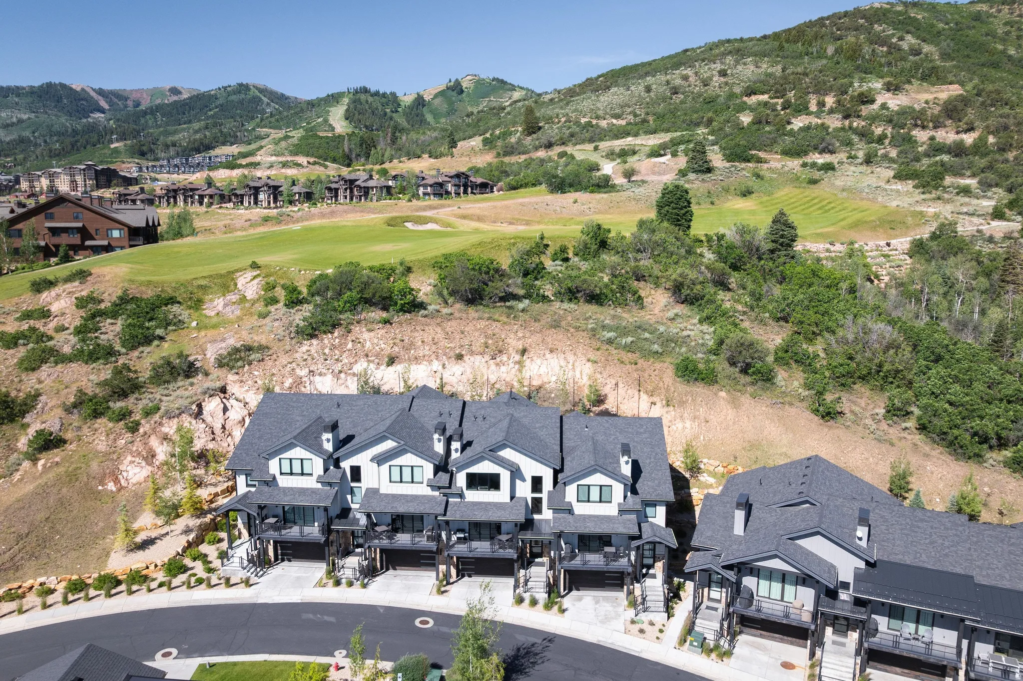 Contemporary multi-level townhomes with dark gray roofs, light-colored siding, and integrated garages