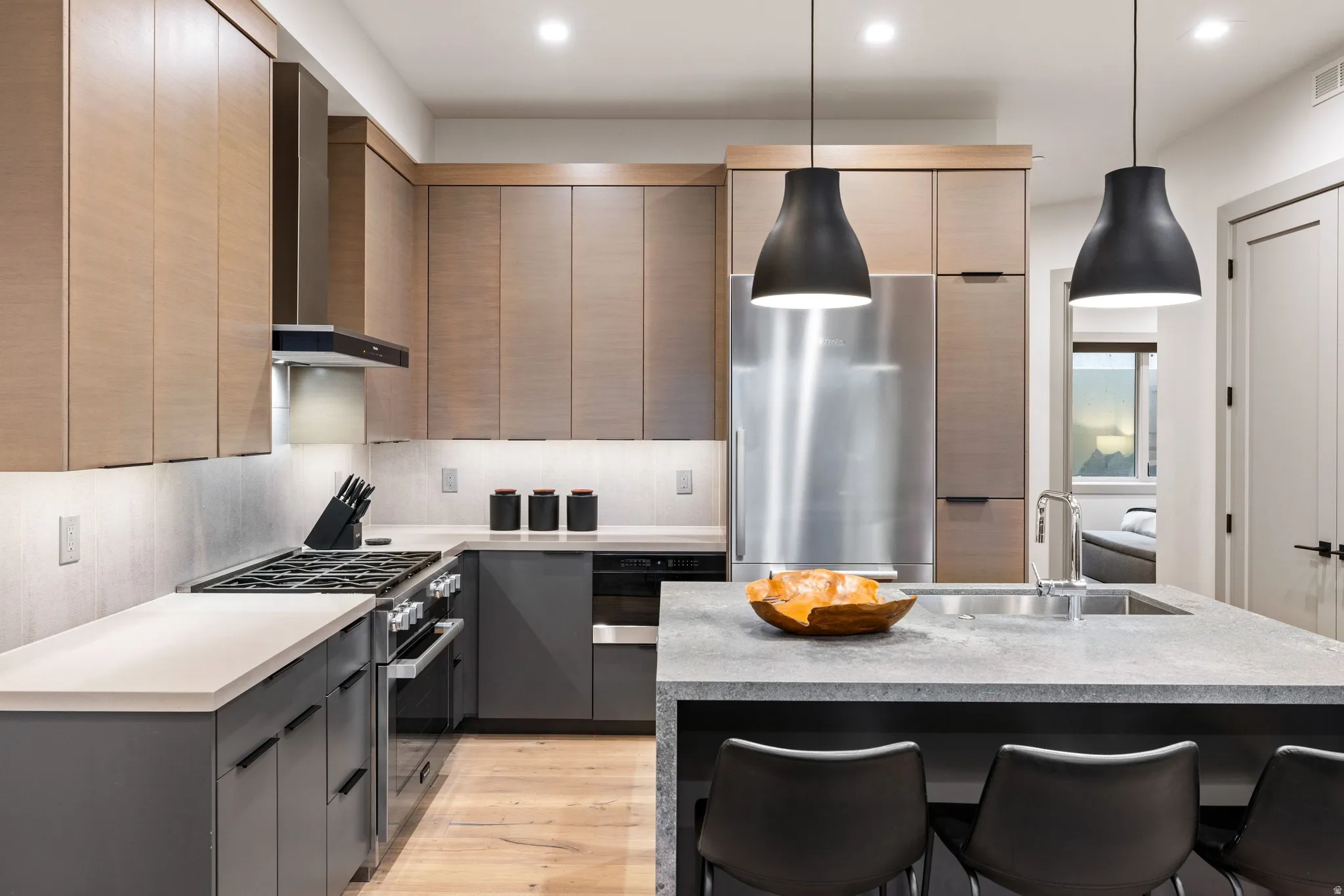 Modern kitchen featuring light wood-finish cabinetry, dark gray base cabinets, and light countertops