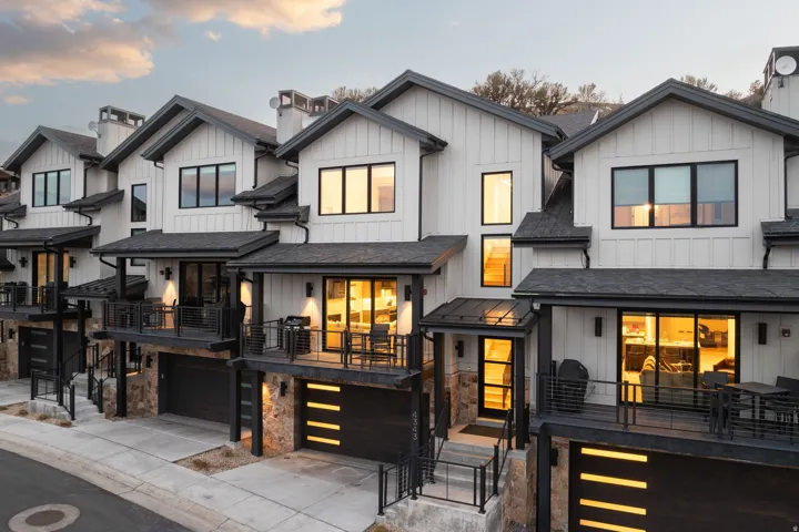 Contemporary townhomes featuring white vertical siding, black trim, and gabled roofs