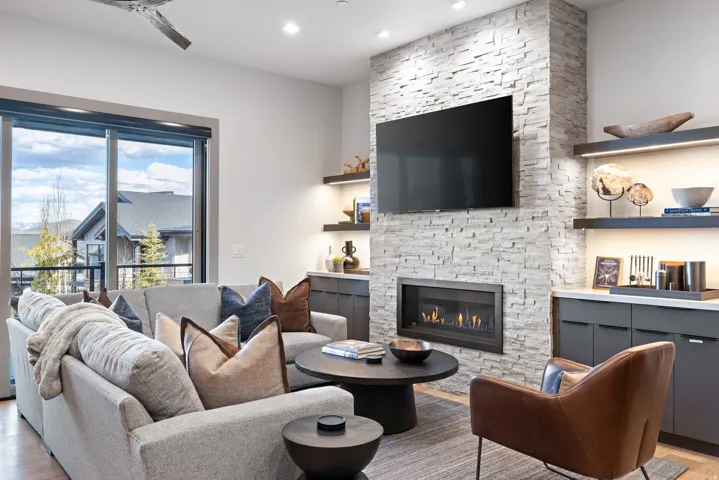 Living area featuring a floor-to-ceiling stacked stone fireplace, a wall-mounted television, and built-in cabinetry with integrated shelving