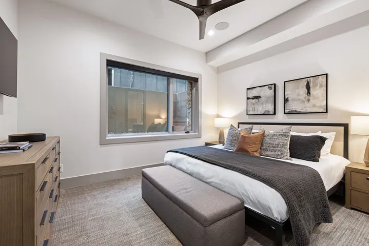 Spacious room featuring a large window, integrated ceiling speakers, recessed lighting, a modern ceiling fan, and textured carpet flooring