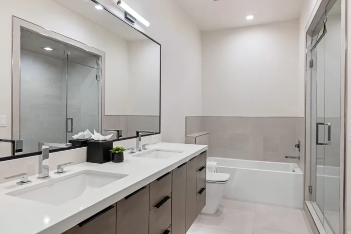 Bathroom featuring a dual vanity with undermount sinks, quartz countertop, and wood-finish cabinetry
