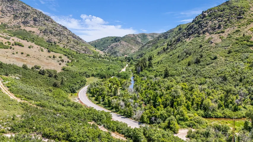 Mountainous landscape featuring a winding road, lush green foliage, and a prominent river