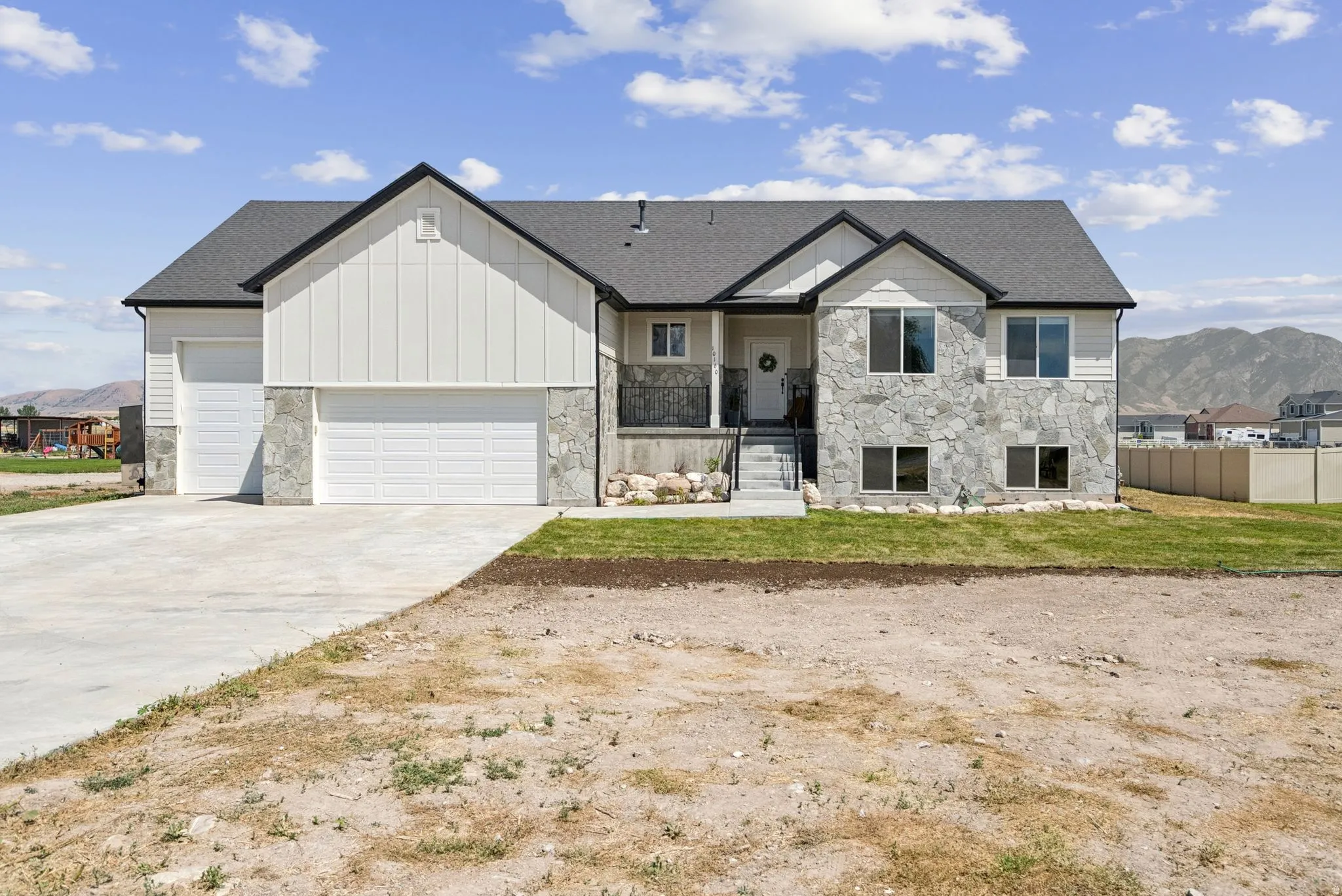 Contemporary exterior featuring stone veneer, vertical siding, a dark shingle roof, and multiple garage doors