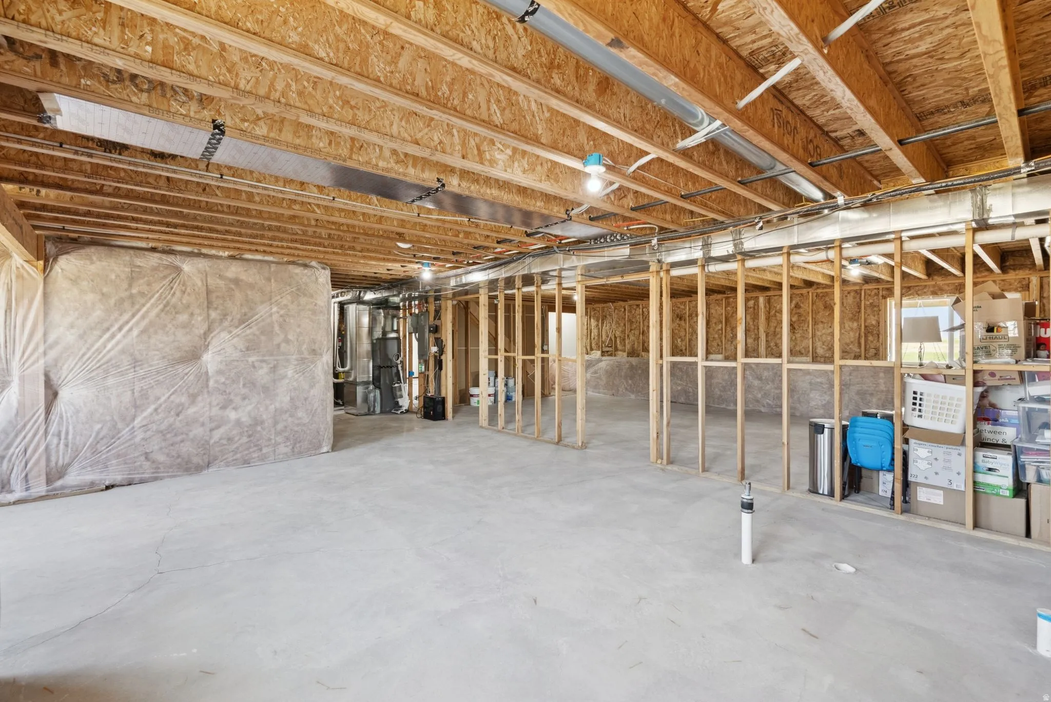 Unfinished basement with exposed wood framing, concrete flooring, and visible overhead utilities