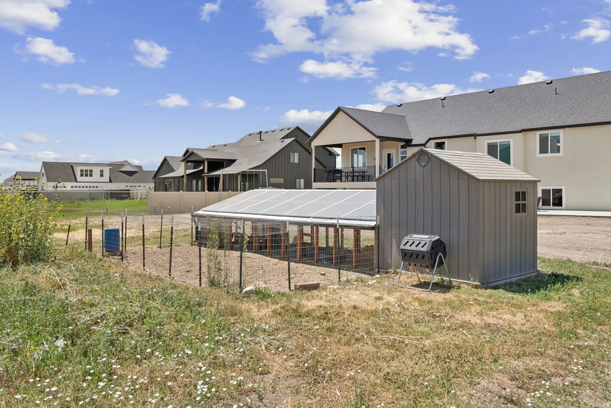 Fenced garden area featuring a storage shed and a covered structure