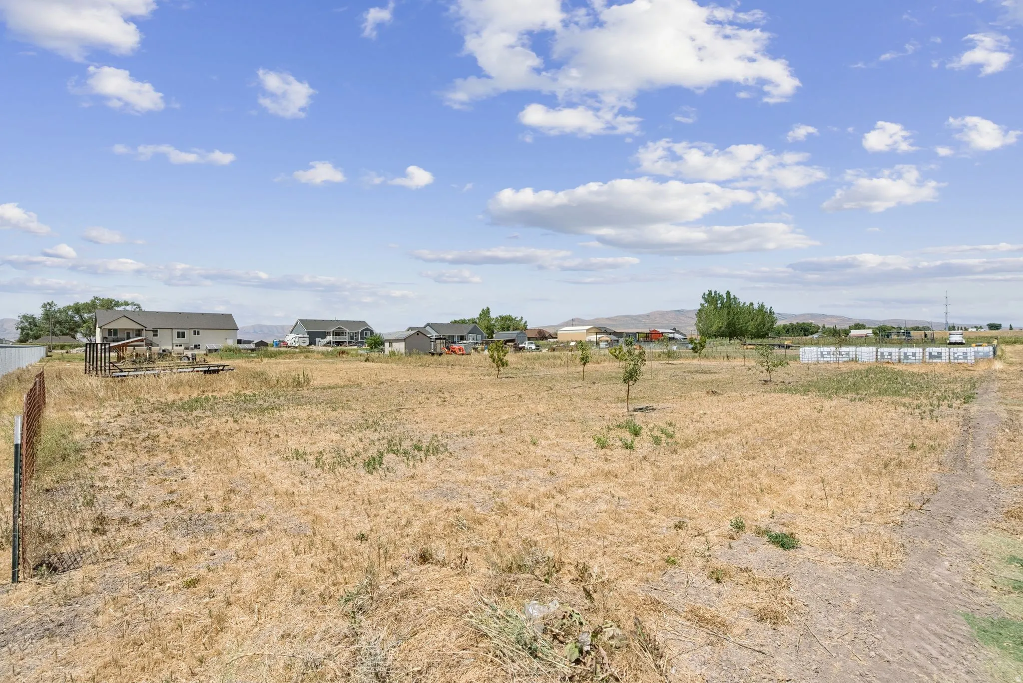 Expansive land parcel featuring a wire fence border and scattered young trees