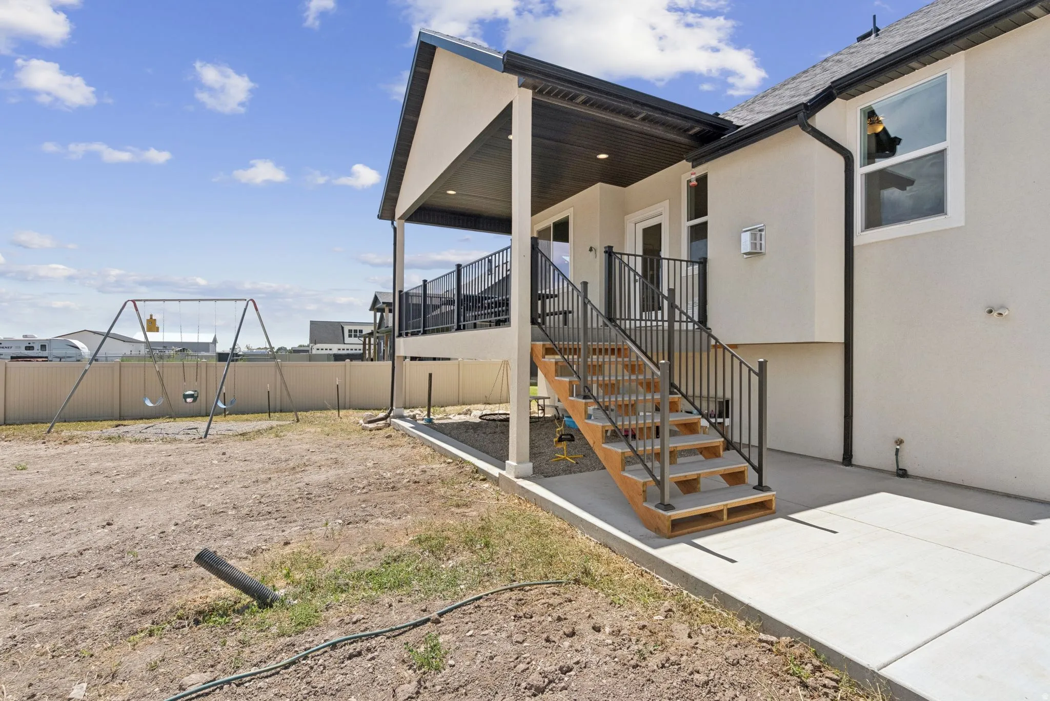 Exterior featuring an upper-level covered patio, an exterior stairway with metal railings, and a concrete patio at ground level