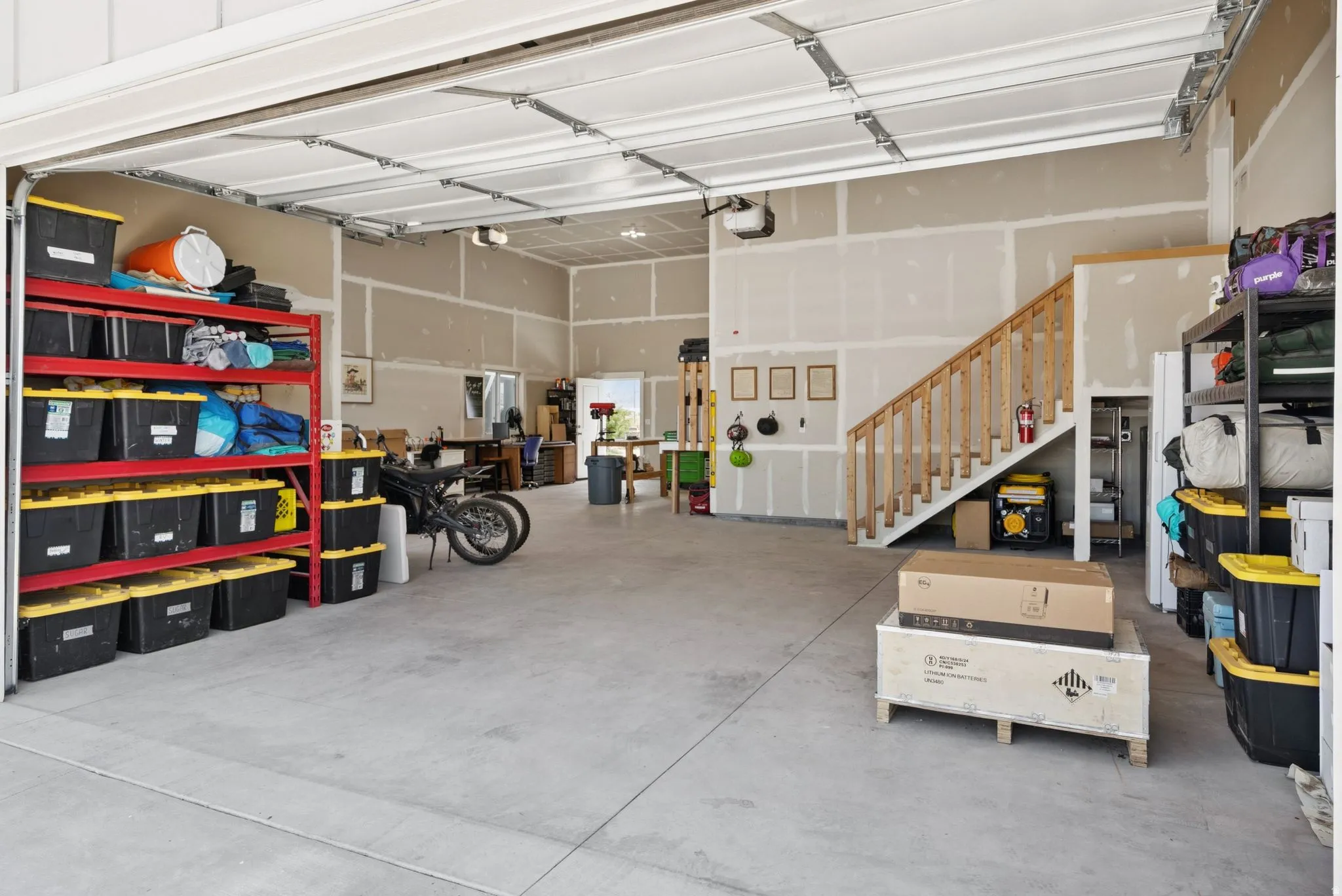 Spacious garage featuring a concrete floor, exposed ceiling joists, and an interior staircase with wood railings