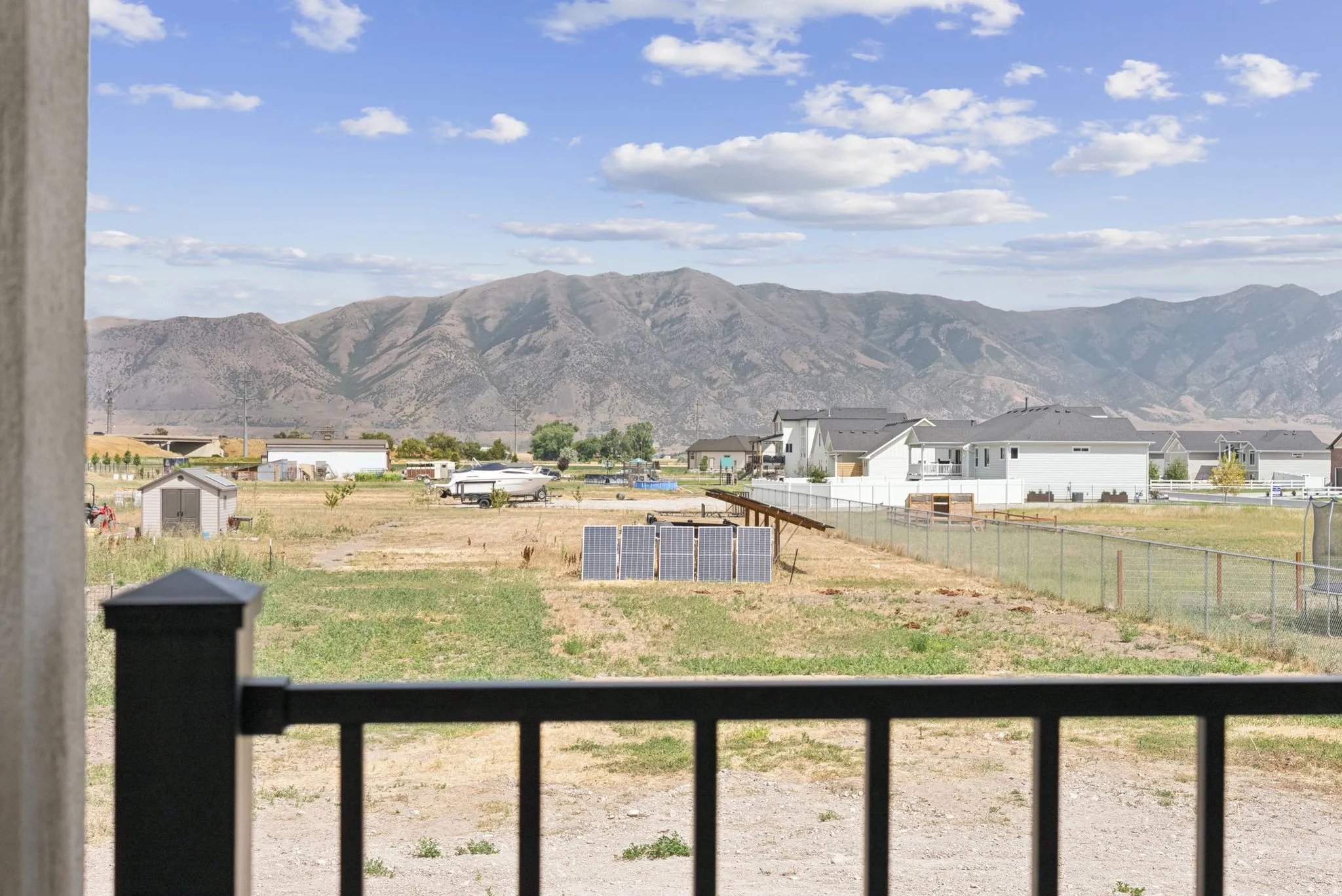 Mountain scenery frames the expansive property, featuring a chain-link fence defining the boundary