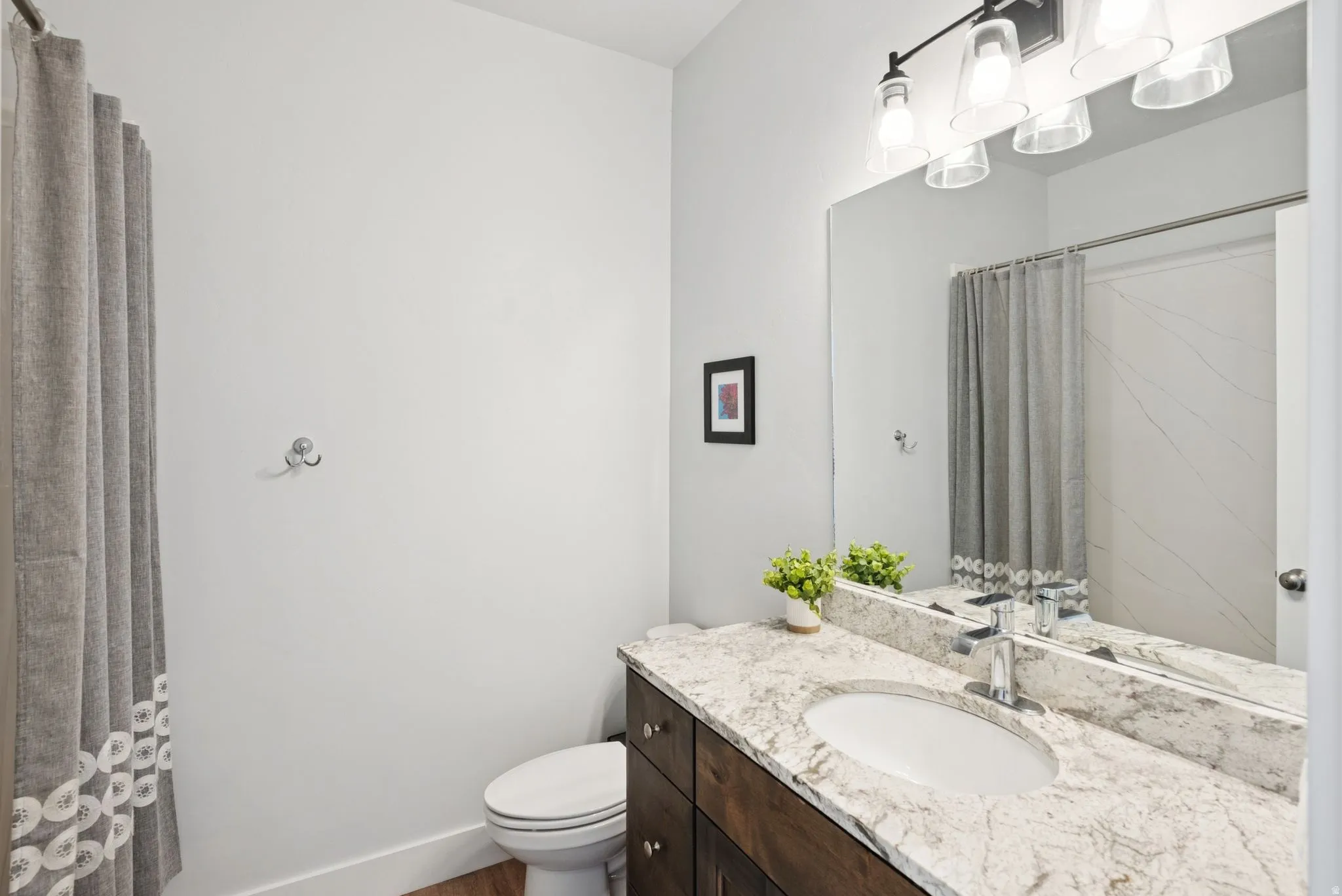 Bathroom vanity featuring a light-colored stone countertop, undermount sink, and dark wood-finish cabinetry