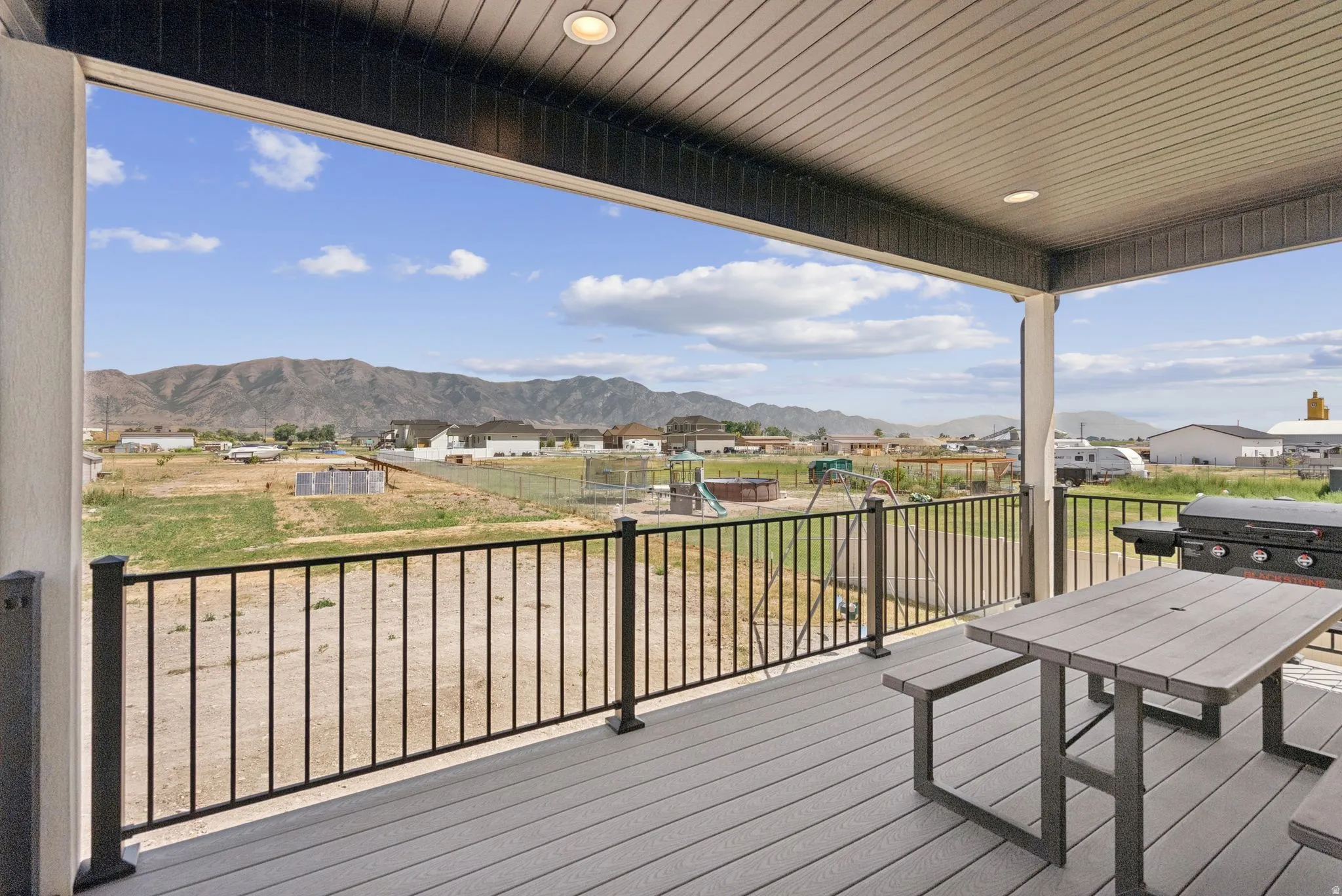 Covered deck featuring composite decking, recessed lighting, and black metal railings