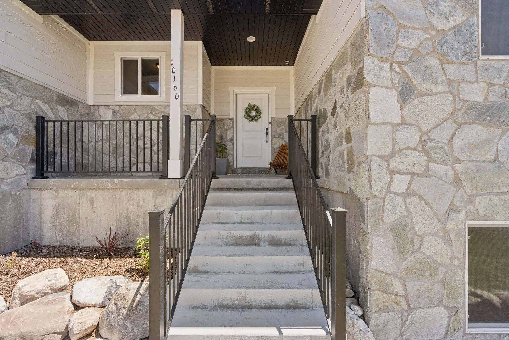 Stone veneer facade and concrete steps leading to a white entry door