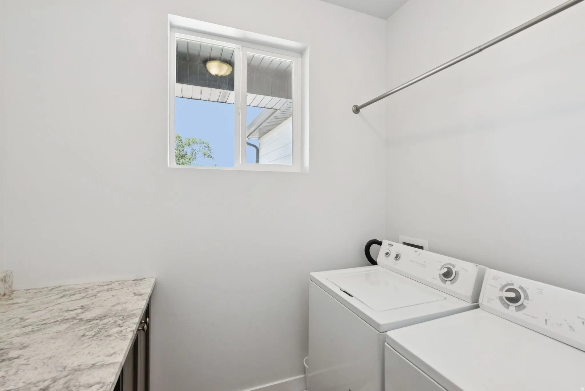 Dedicated laundry area featuring a window, overhead clothes rod, and a spacious countertop with a built-in cabinet