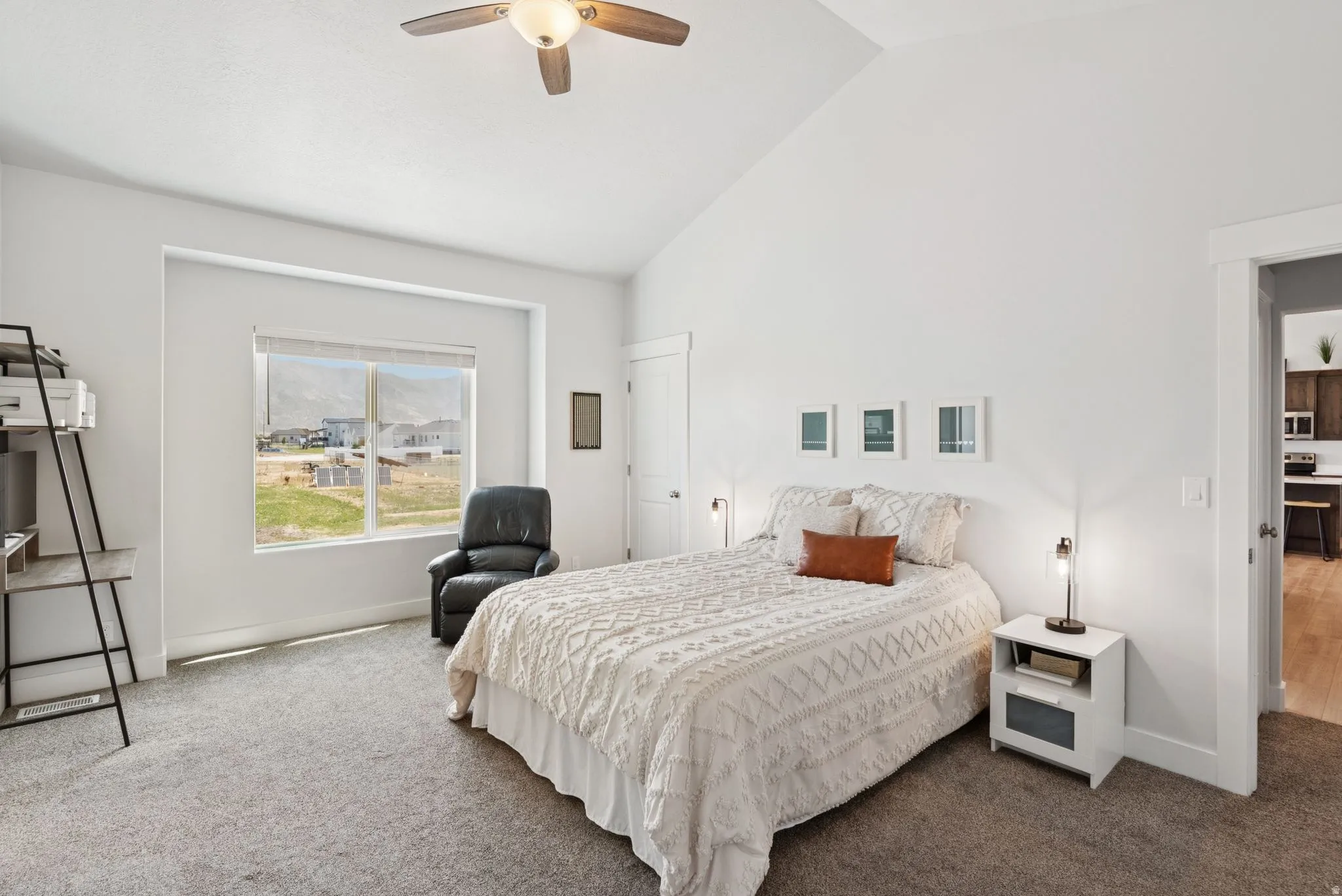 Spacious room featuring vaulted ceilings, neutral-toned carpeting, a large window, and a ceiling fan with integrated lighting