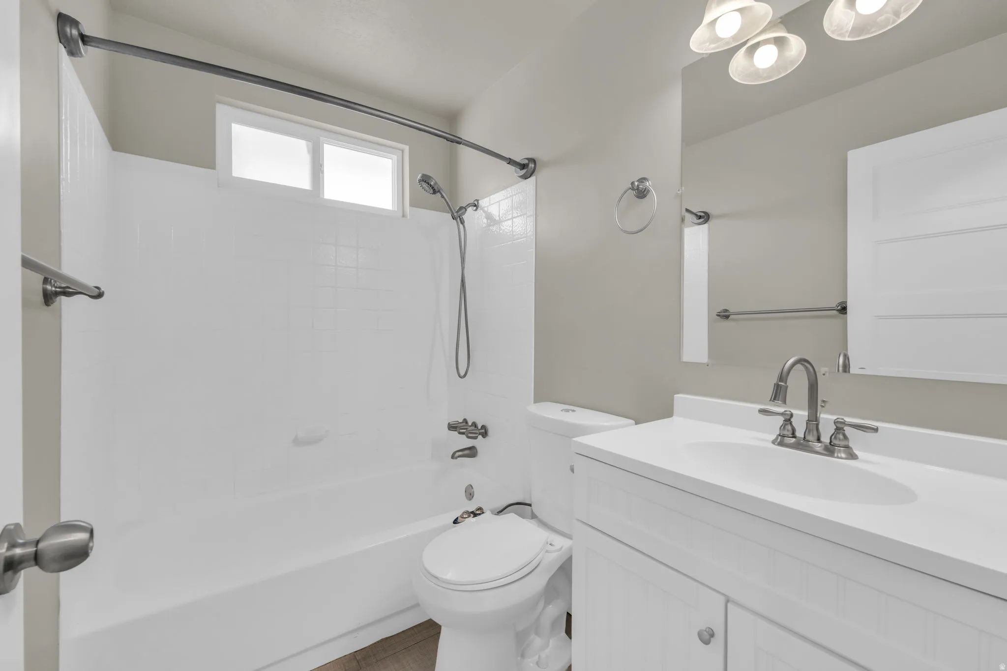 Bathroom featuring a white vanity with an integrated sink, brushed nickel faucet, and overhead lighting