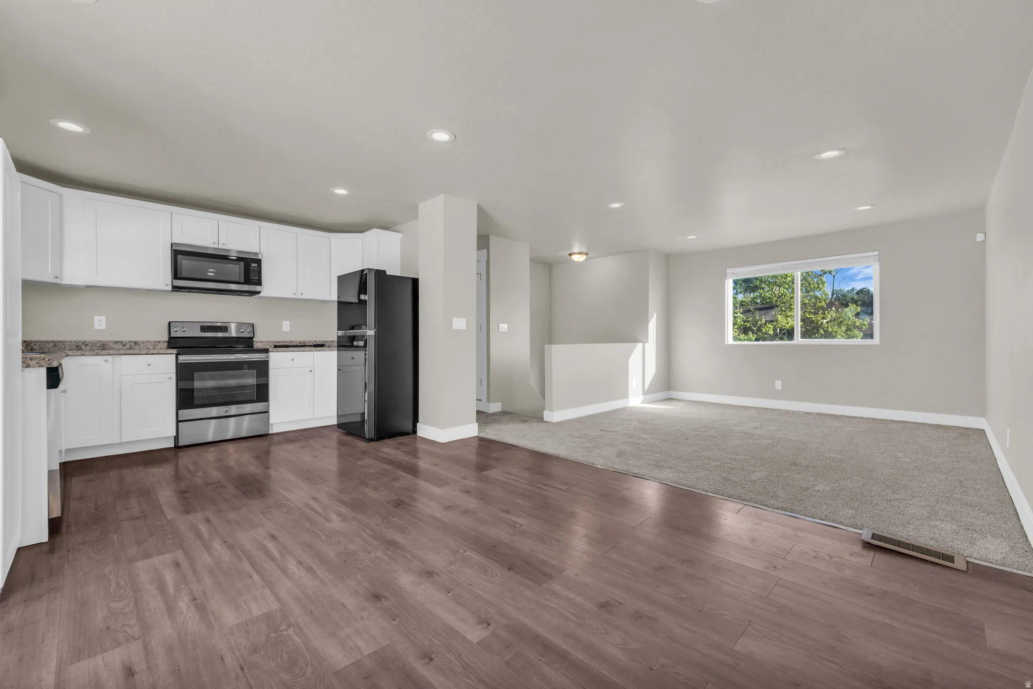 Open-concept living space with wood-finish flooring extending into the kitchen