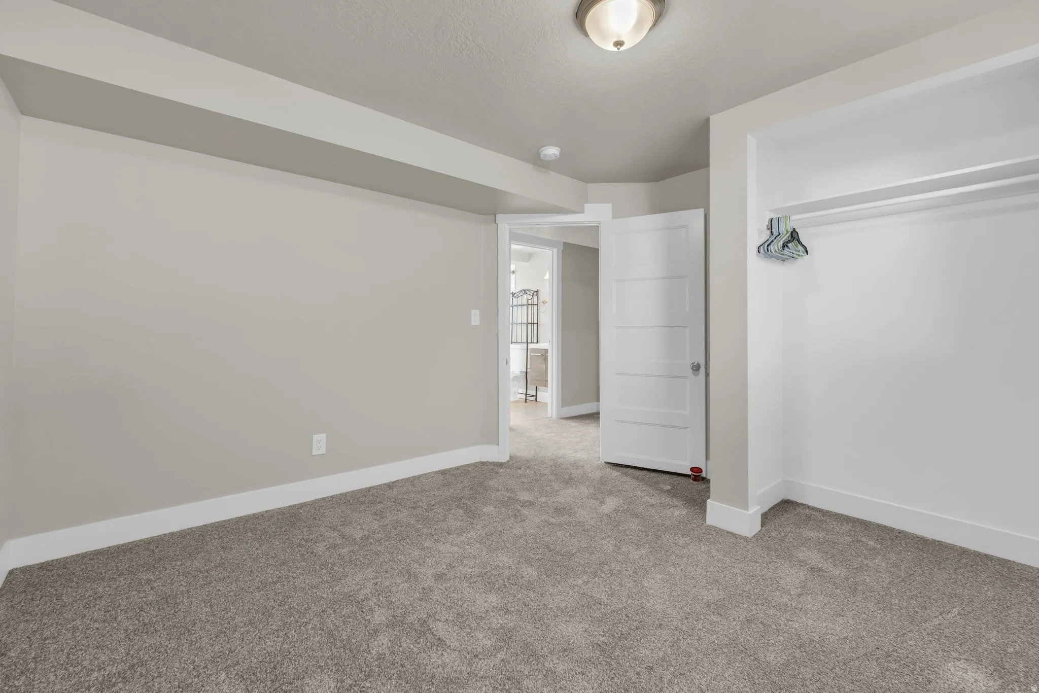 Carpeted room with light grey walls and white baseboards
