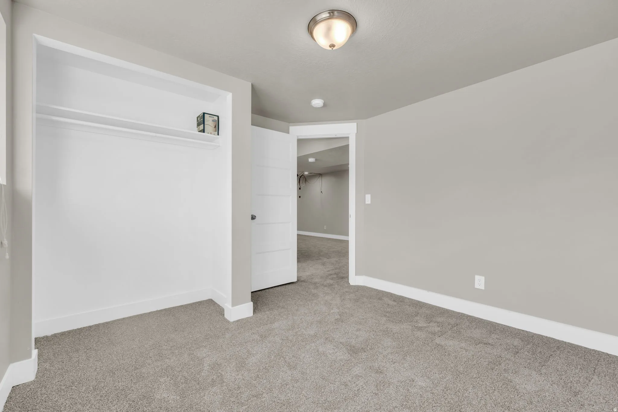 Bedroom featuring a built-in closet with shelving and hanging rod, neutral gray wall paint, and gray carpet flooring