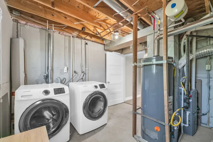 Utility area with exposed ceiling joists, concrete flooring, and a white interior door