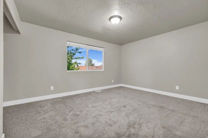 Neutral wall color, wall-to-wall carpeting, and a window with white trim