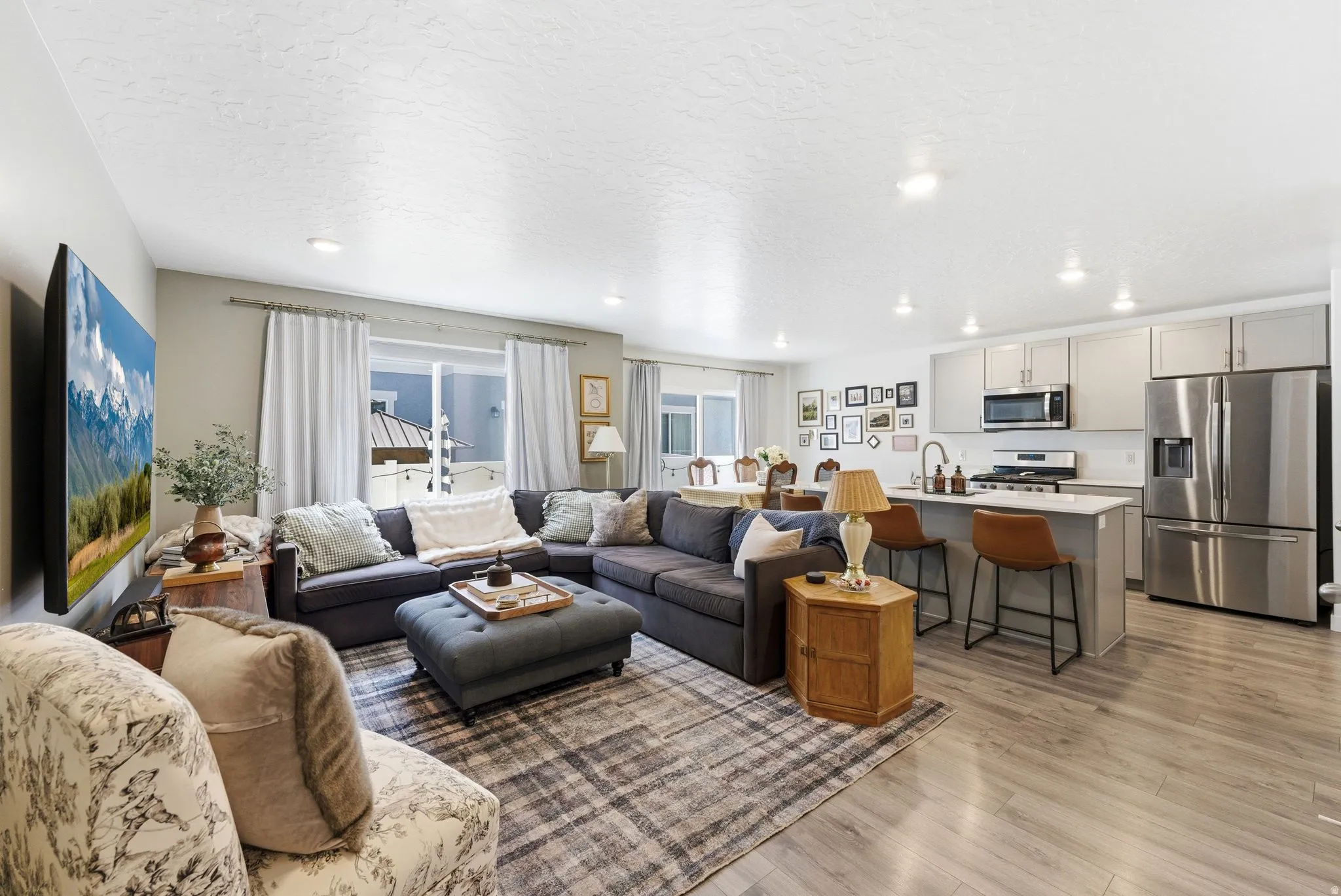 Open-concept living space featuring wood-finish flooring, recessed lighting, and large windows