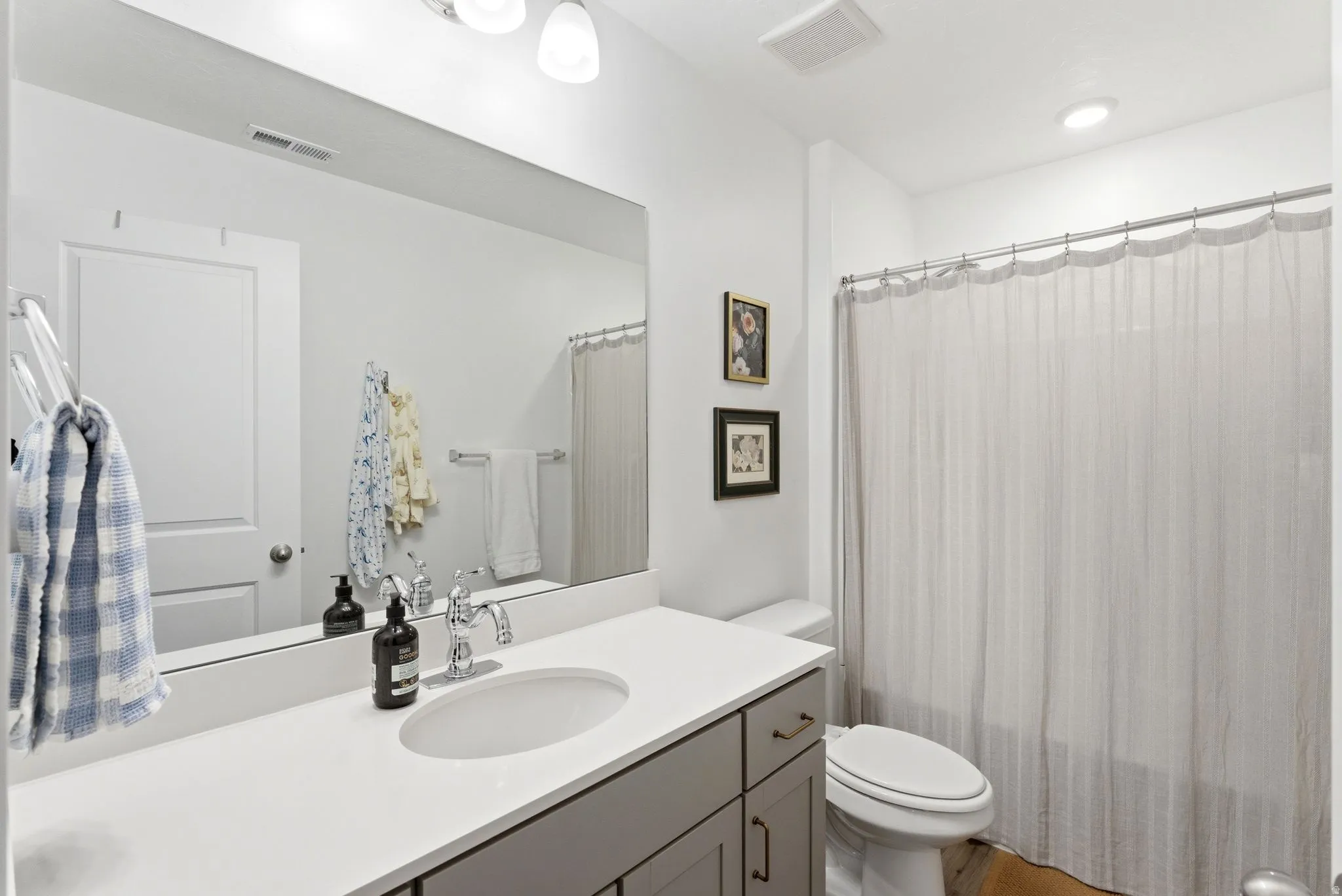 Bathroom featuring a single vanity with a white countertop and undermount sink, complemented by a chrome faucet