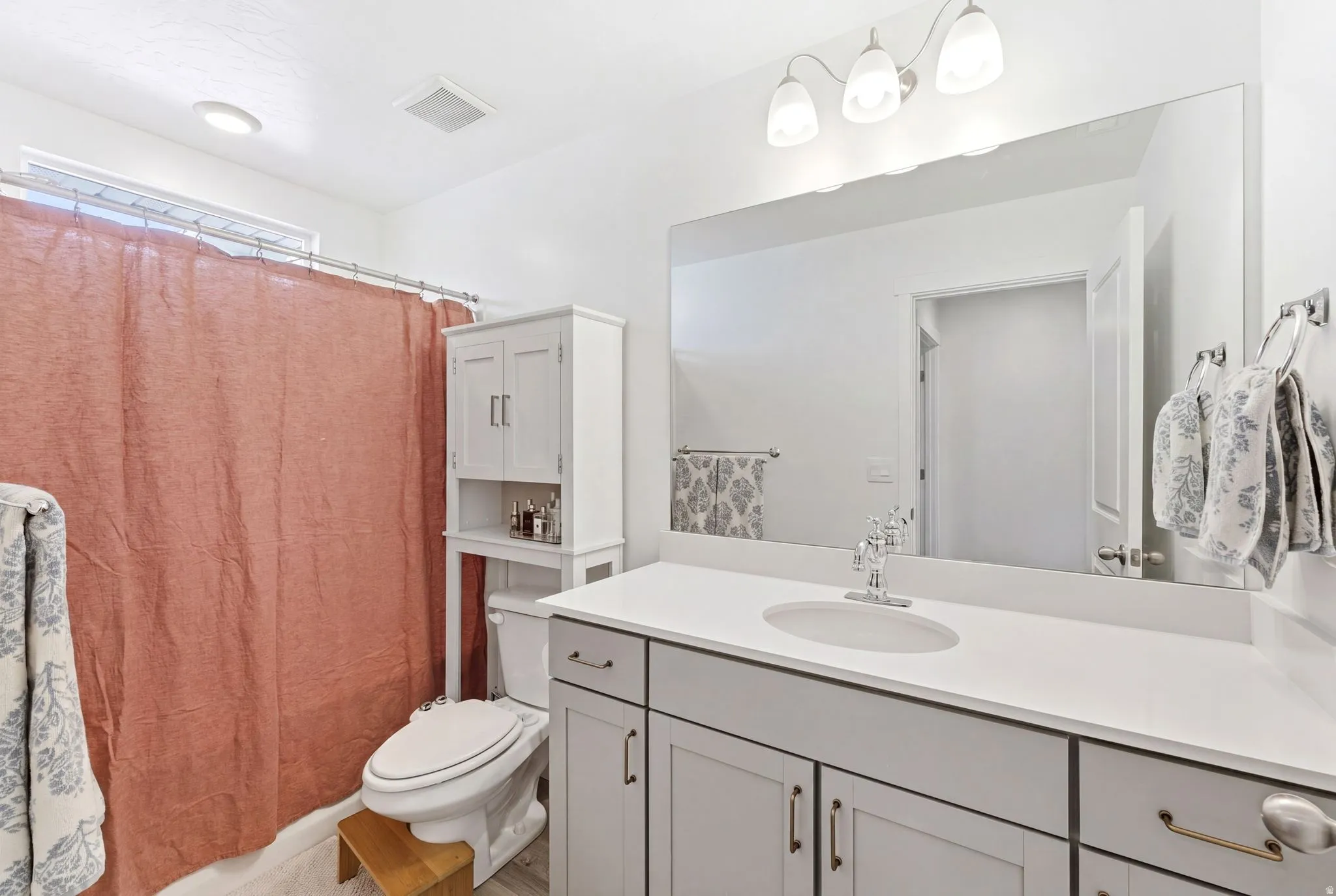 Bathroom featuring a single vanity with a white countertop, an undermount sink, and a chrome faucet