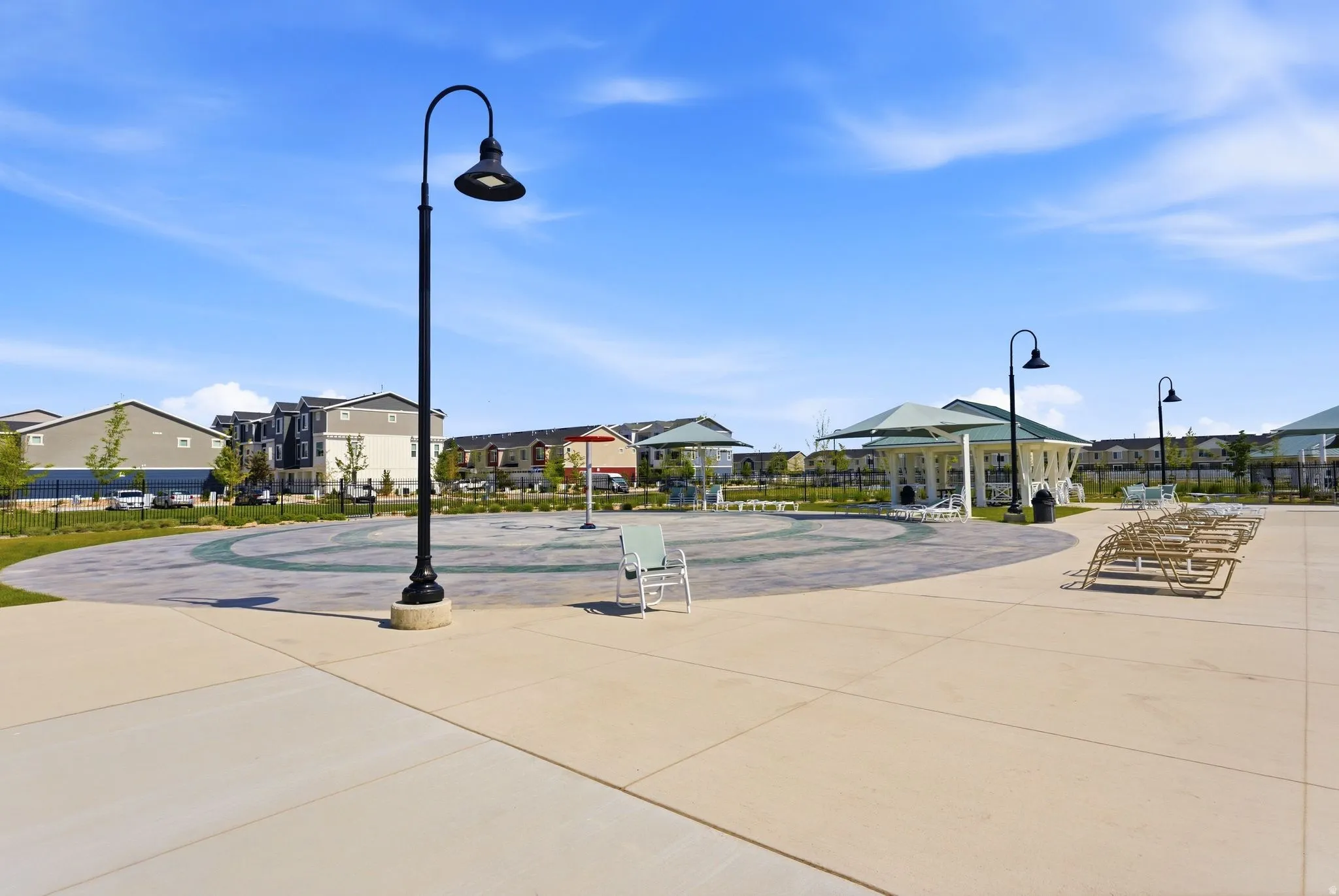 Community amenity area featuring a paved splash pad, multiple covered cabanas, and lounge seating