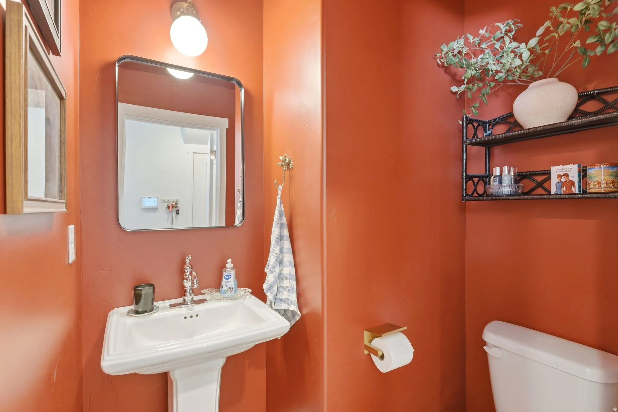 Bathroom featuring a white pedestal sink with polished chrome fixtures, rounded rectangular mirror, and an overhead vanity light