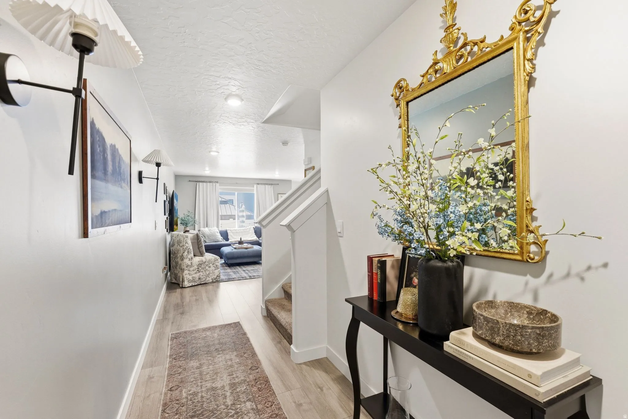 Foyer featuring light wood-finish flooring, a decorative gold-framed mirror, and a built-in console table