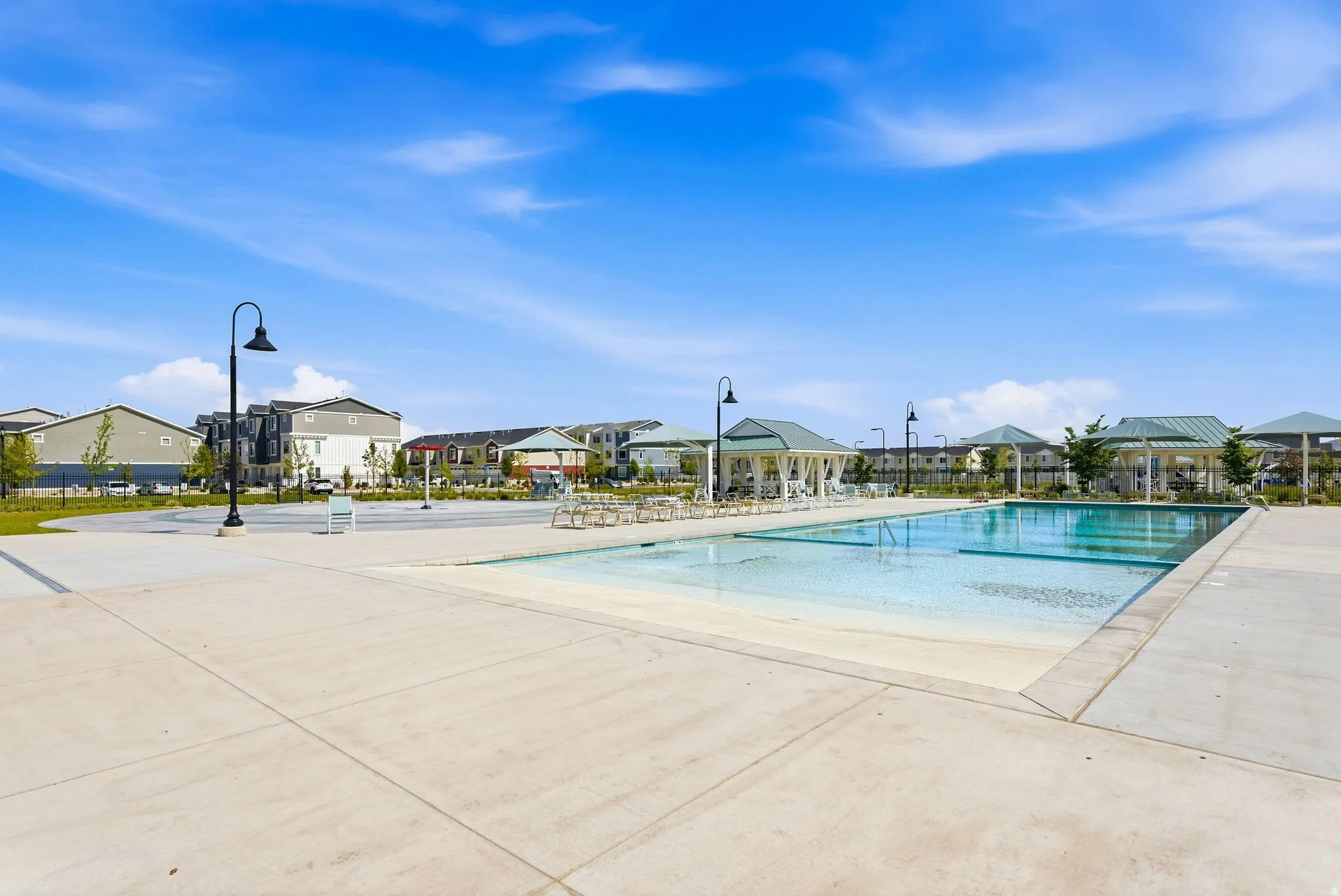 Community swimming pool with a sun shelf and concrete deck