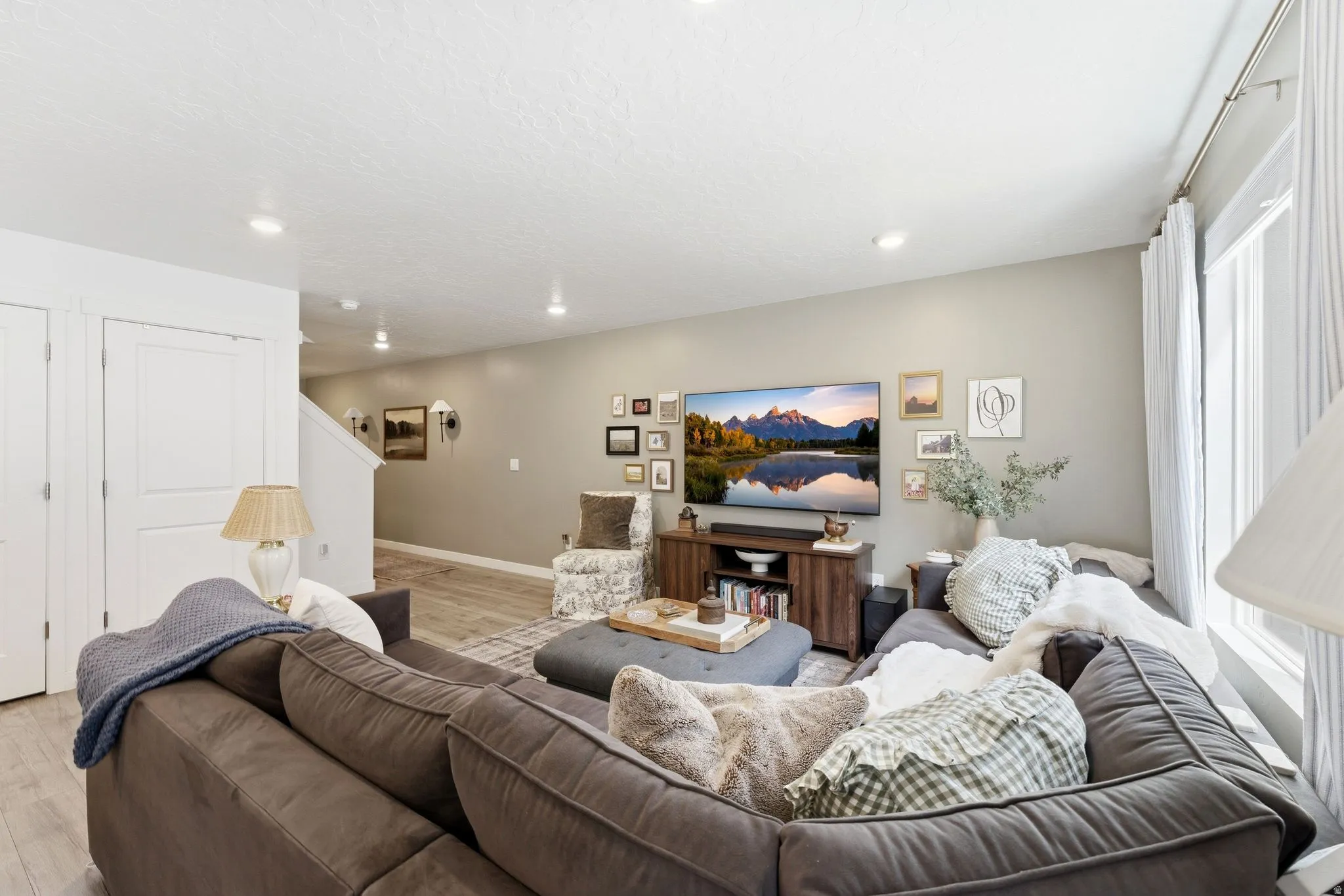 Spacious living area featuring recessed lighting, light-toned walls, and wood-finish flooring