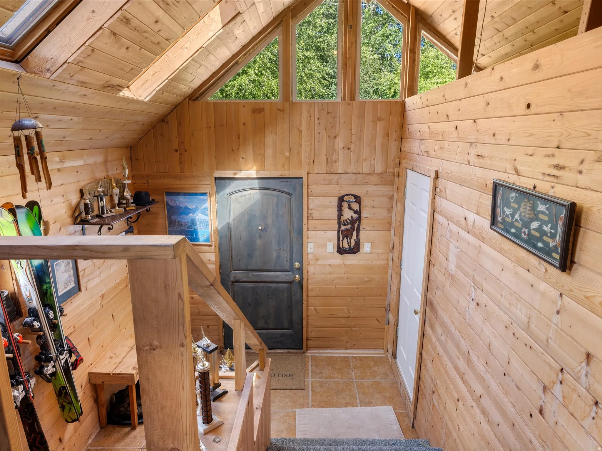 Vaulted ceiling entryway featuring natural wood paneling, an arched transom window, a built-in shelf, and tiled flooring