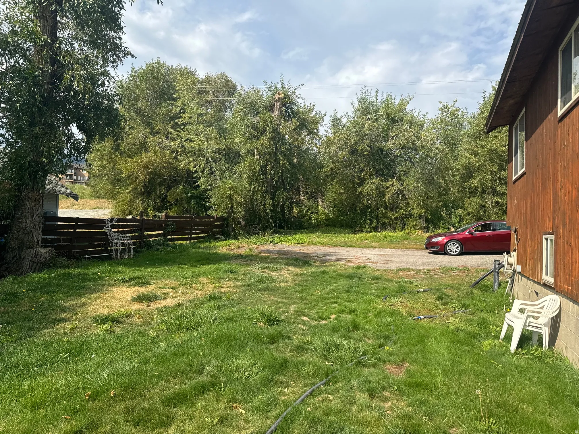 Expansive grassy yard with mature trees and a wood fence