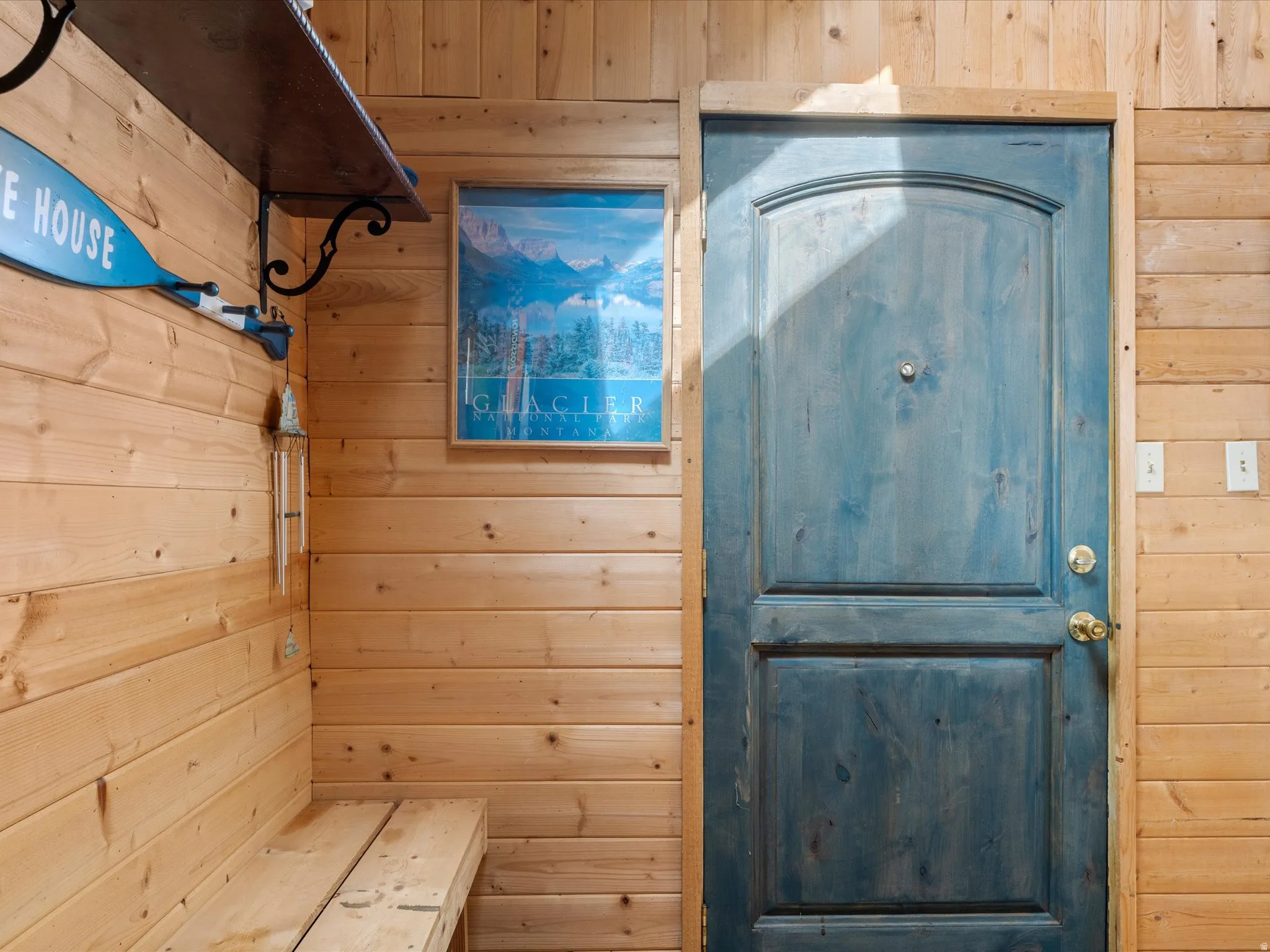 Wood-paneled interior walls featuring a stained wood entry door with brass hardware