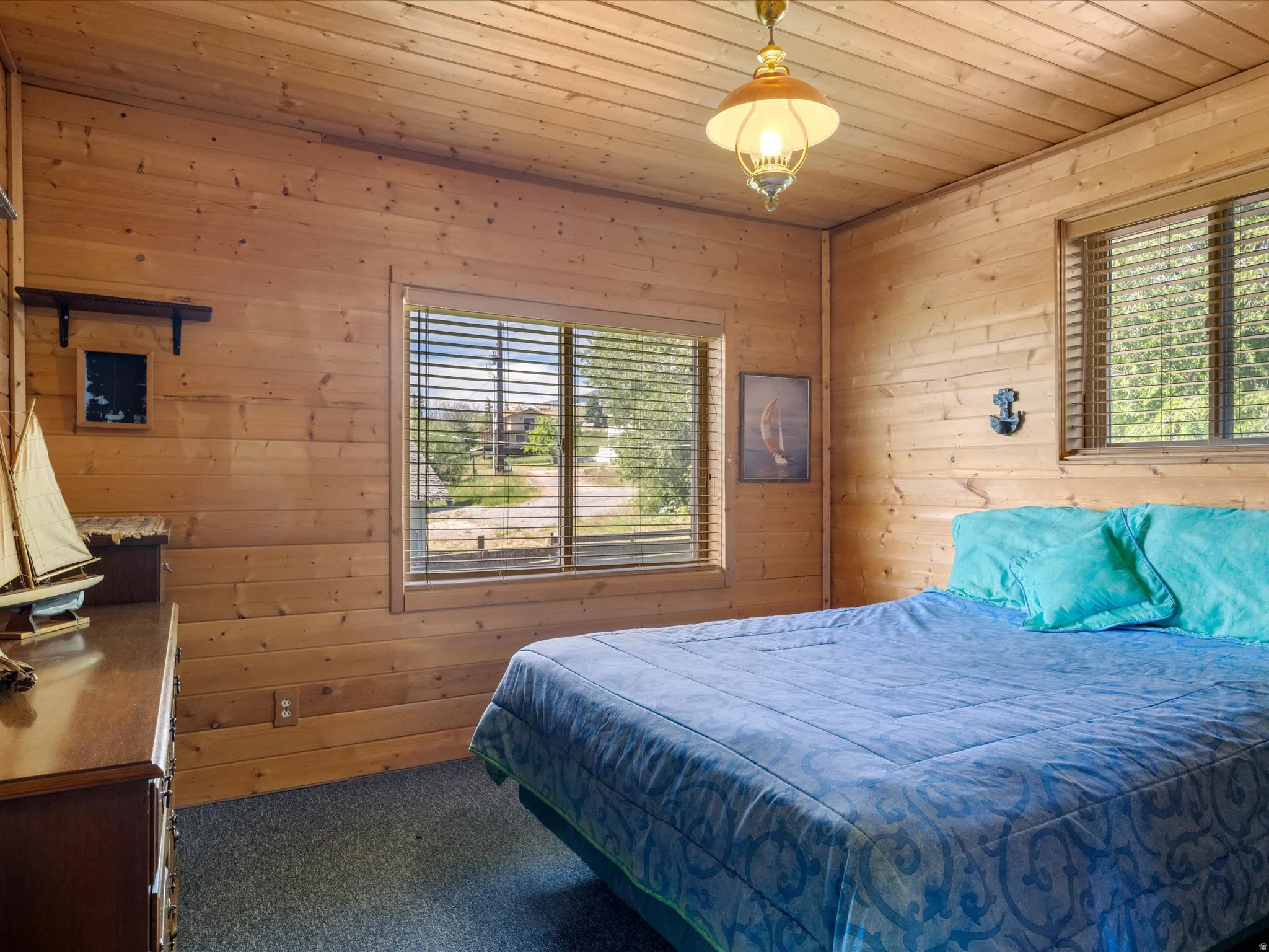 Wood-paneled room featuring dual windows with blinds, a wood-finish ceiling, and wall-mounted light fixtures