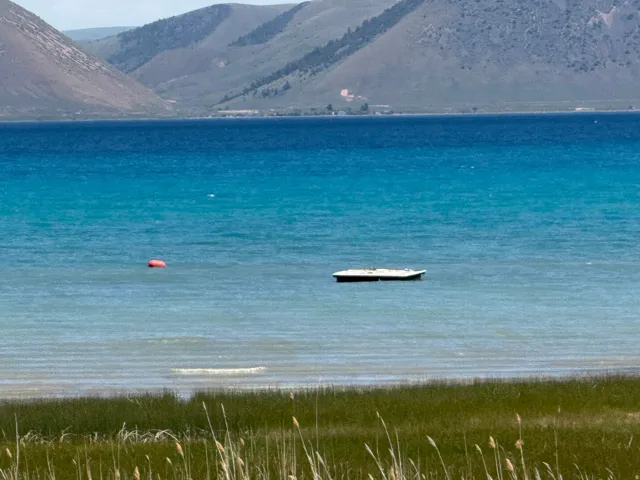 Expansive body of water with varied blue and turquoise hues, bordered by distant mountains