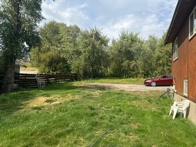 Expansive grassy yard with mature trees and a wood fence