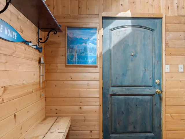 Wood-paneled interior walls featuring a stained wood entry door with brass hardware
