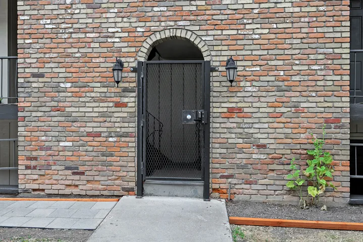 Brick exterior featuring an arched entryway, decorative metal security gate, and dual exterior sconces