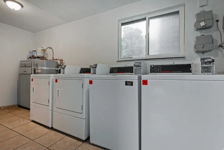 Dedicated laundry area featuring multiple commercial-grade washers and dryers