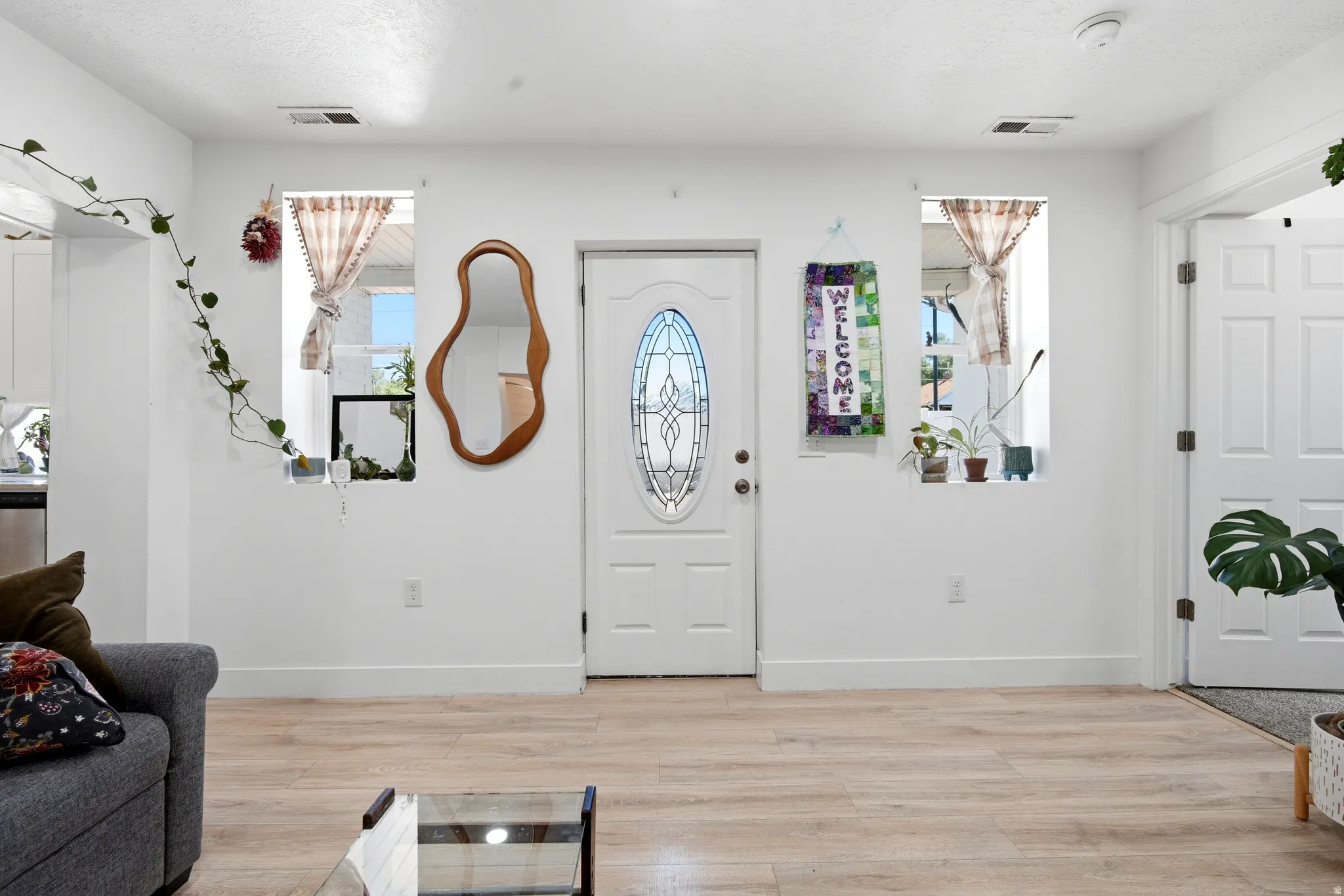 Entryway featuring a white door with an oval stained-glass insert, flanked by two windows