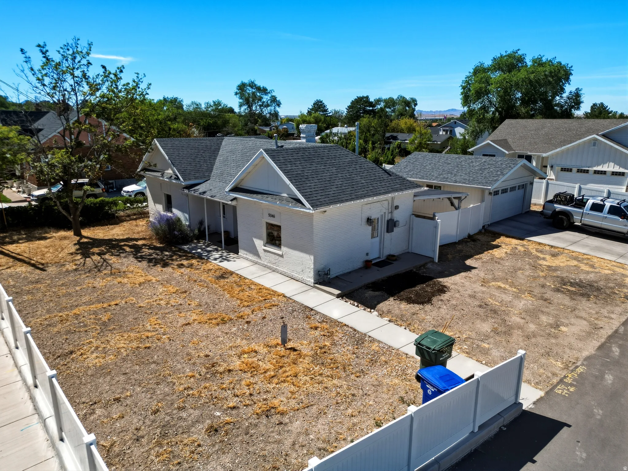 Single-story residence featuring a white painted brick exterior and a dark shingle roof