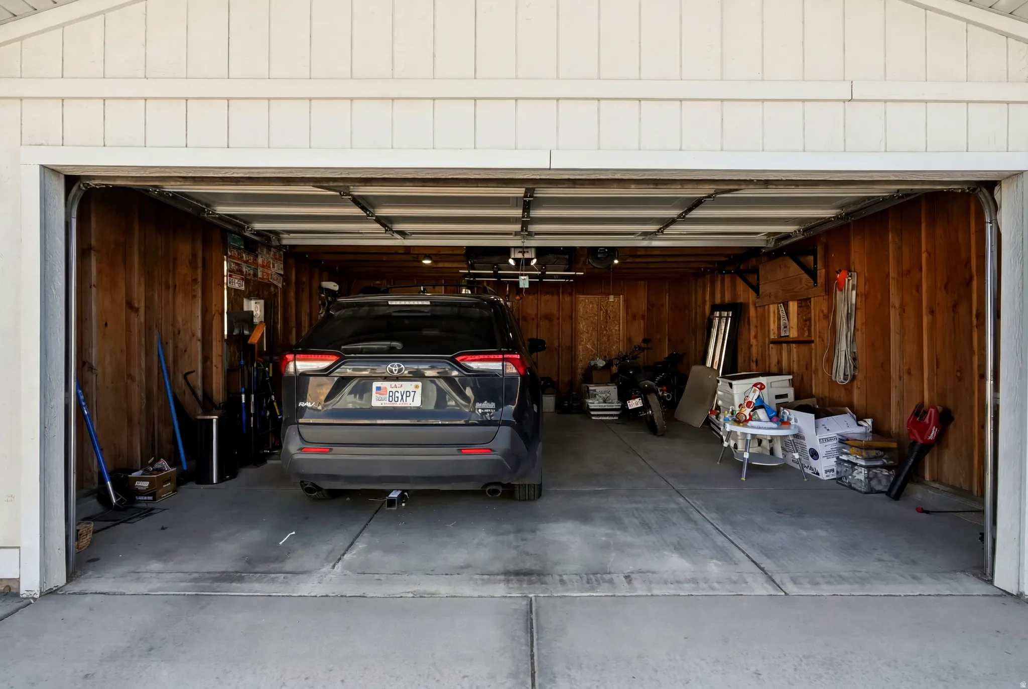Two-car garage featuring concrete flooring and wood-paneled walls