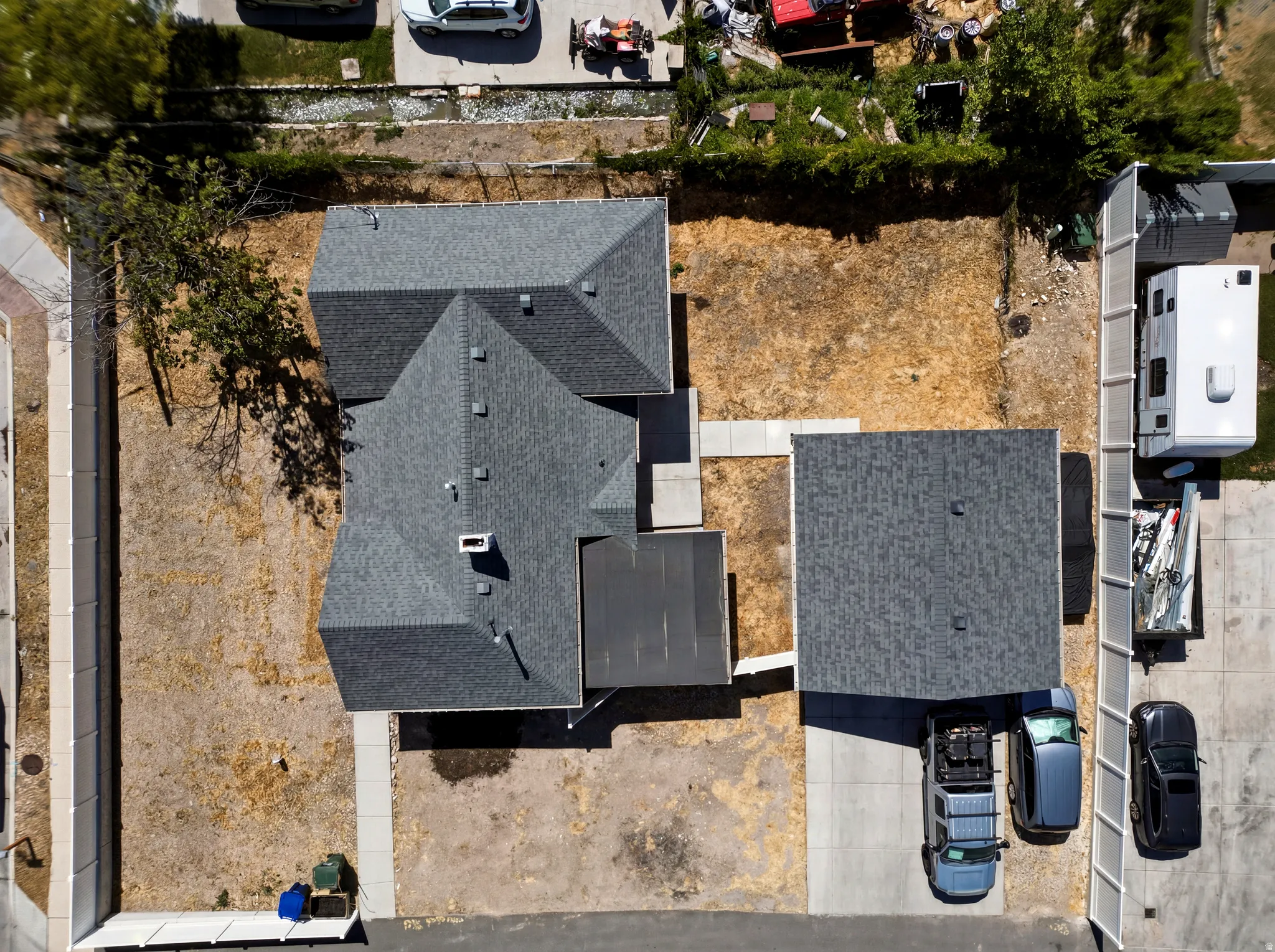 Property featuring a main residence with a multi-gabled roofline, a detached structure with a pitched roof, and concrete pathways